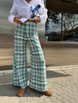 Pantalón de lino italiano con diseño de cuadros escoceses en tonos verdes y blancos. Presenta un corte de pierna ancha tipo oxford y tiro medio-alto.