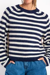 Sweater de lana con rayas horizontales en tonos rojo, rosa, beige y marrón. Presenta costuras decorativas en los laterales y puños en color violeta.