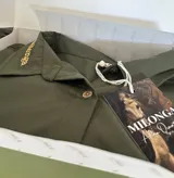 Camisa de corte oversize tipo boyfriend, color verde oliva, con cuello clásico, cierre frontal de botones de nácar y detalle bordado en el cuello.