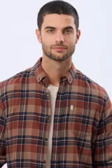 Camisa de viyela a cuadros en tonos marrón, azul marino y gris, con cuello clásico, cierre frontal con botones, mangas largas y un bolsillo en el pecho.