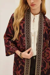 Kimono de viscosa con estampado ikat en tonos bordó y rosado, con bordes decorados con detalles geométricos y mangas tres cuartos.