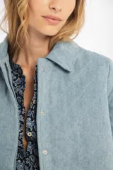 Chaqueta capitoneada celeste vintage de denim de algodón 100% natural pre-lavado y suavizado, con bolsillos laterales, botones a presión escondidos y ruedo curvo en los costados.