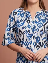 Blusa de gasa estampada en tonos azules y negros, marca Sioni. Tiene cuello a la base con escote en V, abertura central con botones y mangas tres cuartos fruncidas.