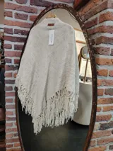 Chal triangular tejido con lana merino color crudo, con terminaciones de flecos largos.