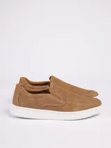 Zapatilla tipo slip-on color marrón, con textura microperforada en la parte superior y suela de goma blanca. Presenta costuras decorativas a la vista.