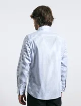 Camisa de corte clásico confeccionada en tejido oxford, con diseño de rayas verticales en tonos azul y blanco. Presenta cuello abotonado, cierre frontal con botones y bolsillo en el pecho con detalle de etiqueta bordada.