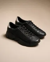Championes urbanos de mujer con diseño de malla texturizada en color negro y detalle metálico en tono dorado en el talón. Poseen una suela gruesa y resistente, ideal para uso diario.
