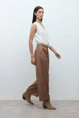 Pantalón de corte sastrero y pierna ancha, confeccionado en lyocell. Presenta pinzas en la cintura, cierre frontal con botón y bolsillos laterales. Incluye un cinturón fino de cuero con hebilla metálica.