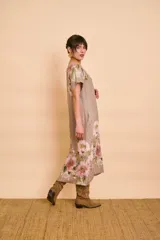 Vestido midi de lino color tostado con estampado floral en tonos rosados y verdes, cuello redondo, mangas cortas y bolsillos laterales.