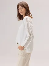 Remera de manga larga color gris claro, con detalle de franjas laterales en contraste color amarillo en las mangas. Presenta un diseño holgado y moderno.