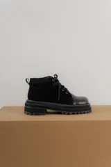 Borcegos de punta cuadrada con diseño acordonado, combinando paneles de cuero texturizado y gamuza en tonos marrones. Presentan una suela track gruesa de goma negra y cordones negros.
