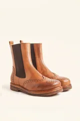 Bota tipo Chelsea de cuero vacuno color suela, con diseño brogue en la puntera y laterales. Presenta paneles elásticos laterales en color marrón oscuro, tirador trasero y suela de goma con plataforma.