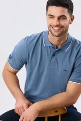 Remera polo de piqué azul marino, con cuello y puños de mangas cortas con ribete blanco en contraste, cierre frontal de dos botones y pequeño logo bordado en el pecho.