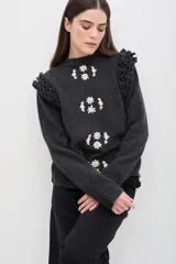 Sweater de lana color celeste, con cuello redondo, mangas largas y volados decorativos en los hombros. Presenta un diseño frontal con bordados florales artesanales y detalles calados verticales que recorren la prenda.