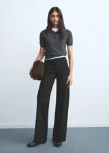 Jeans wide leg tiro alto de color negro, con cierre delantero de cremallera y botón, trabillas para cinturón y dos bolsillos de parche en la parte delantera.