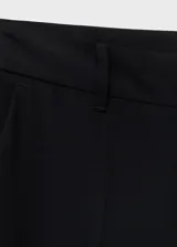 Pantalón de tiro medio color negro, de diseño recto y largo, con trabillas en la cintura, dos bolsillos laterales y cierre oculto con botón, gancho y cremallera.