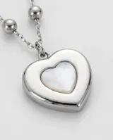 Collar de acero con cadena de eslabones y pequeñas cuentas esféricas, con dije colgante en forma de corazón con incrustación de nácar.