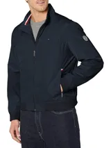 Campera bomber Tommy Hilfiger azul marino con cuello alto, cierre frontal con cremallera, dos bolsillos laterales con cremallera, puños y bajo elásticos. Tiene el logo de Tommy Hilfiger bordado en el pecho y un parche con el logo en la manga izquierda. El interior del cuello tiene detalles en rojo, blanco y azul.