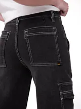 Pantalón cargo de denim color negro con costuras a contratono en blanco. Presenta un corte relajado, tiro alto, bolsillos laterales tipo cargo con solapa y bolsillos de parche delanteros y traseros.