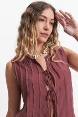 Blusa sin mangas color gris claro con textura rayada vertical y lazo ajustable en el escote.