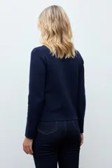 Chaqueta tejida de punto en color azul marino, con diseño de doble botonadura frontal y bolsillos aplicados. Presenta un cuello desmontable en tono claro y mangas largas.