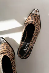 Zapato tipo slingback color crema con punta afilada y detalle metálico plateado. Tacón bloque color negro.