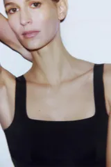 Vestido midi negro, entallado, con escote en pico y tirantes anchos. Presenta detalle de costuras verticales a tono que simulan entredós.