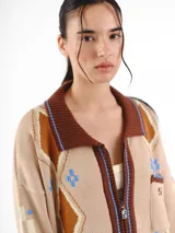 Campera tejida en jacquard con cierre frontal, cuello tipo polo y bolsillos delanteros. Diseño multicolor con estampado geométrico de rombos y detalles bordados a mano.