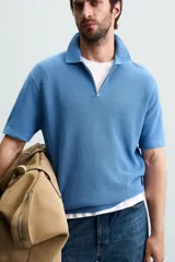 Polo de manga corta, color azul medio, tejido en punto perlado con cuello solapa y cierre frontal de cremallera.