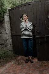 Buzo de punto con diseño a rayas horizontales en blanco y negro. Presenta cuello alto con cierre frontal parcial y mangas largas con puños acanalados.