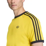 Remera Adidas de manga corta color amarillo, con cuello redondo y ribetes negros en cuello y mangas. Cuenta con las clásicas tres tiras negras en los hombros y el logo del trifolio bordado en el pecho.