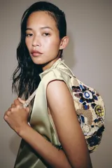 Bolso de mano con cuerpo cubierto de abalorios y apliques florales bordados, con asa corta y cierre de cremallera.