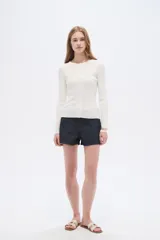 Remera de manga larga al cuerpo confeccionada en viscosa, de color blanco, con cuello a la base y cierre frontal de botones.
