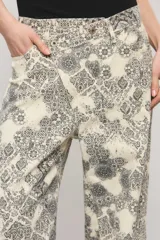Pantalón de tiro medio y calce holgado, confeccionado en 100% algodón de peso medio con un estampado exclusivo de diseño ornamental en tonos blanco y gris oscuro. Cuenta con una cartera asimétrica cruzada en la cintura, bolsillos y sutiles desgastes manuales con pequeñas roturas localizadas.