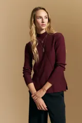 Polera de tejido acanalado color bordó, con cuello alto y diseño geométrico en relieve que estiliza la figura. Presenta un ajuste al cuerpo y mangas largas.