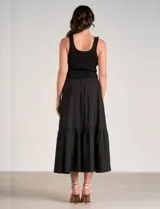 Vestido maxi combinado negro de la marca Elan, con torso de punto acanalado con escote en V pronunciado y breteles anchos. Cuenta con corte a la cintura y falda larga fluida con volumen, bolsillos laterales y volante fruncido en el ruedo.
