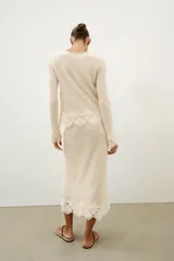 Falda midi de tejido rústico en color beige, con tiro medio, cintura elástica y detalle de aplicación de crochet en el bajo.