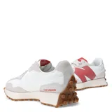 Championes urbanos New Balance modelo 327, con diseño retro inspirado en los años 70. Presentan una base de material sintético blanco con superposiciones de gamuza en tono gris claro, destacando el logo 'N' lateral en color rosado. Incluyen entresuela de espuma EVA y suela de goma dentada que se extiende hacia el talón.