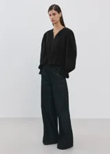 Blusa de algodón negra con detalles florales bordados, cuello en pico con cierre de lazo, manga larga abullonada y diseño recto con vuelo en la cintura.