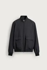 Cazadora regular fit negra de tejido técnico repelente al agua, con cuello alto, cierre frontal de cremallera, bolsillos frontales con solapa y acabados en rib en puños y cintura.