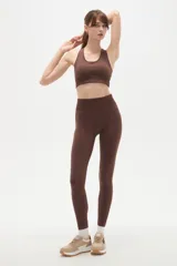 Calza deportiva de tiro alto y ajuste ceñido al cuerpo, confeccionada en tejido elástico de color marrón.