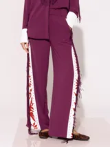 Pantalón sastrero largo color borgoña con recortes a contra tono y estampado floral en el delantero. En ambos laterales lleva flecos de tela base al tono.