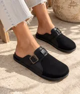 Zueco negro de cuerina con puntera de gamuza, capellada combinada y tira lateral ajustable con hebilla metálica de tono bronce.
