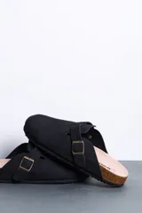 Sandalias Cech estilo zueco color negro, con diseño cerrado en la parte delantera, tira ajustable con hebilla metálica dorada, plantilla anatómica y suela tipo corcho.