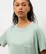 Remera de algodón con calce oversized, cuello redondo y mangas cortas. Presenta un diseño minimalista con un pequeño estampado de texto en el pecho y un acabado lavado en color verde menta.