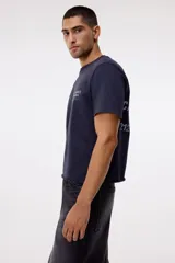 Remera de algodón color gris oscuro con cuello redondo y estampado pequeño en el pecho con texto en color blanco.