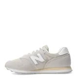 Championes urbanos New Balance modelo 373, color gris claro con detalles en beige y blanco. Confeccionados en una combinación de gamuza y malla, presentan el logo "N" característico en los laterales y una suela de goma con entresuela amortiguada.