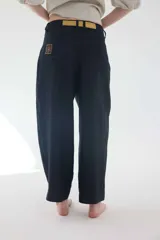 Pantalón de lino marrón de tiro medio, con calce holgado y diseño de piernas amplias. Cuenta con bolsillos traseros, trabillas para cinto y un pin bordado en contraste.
