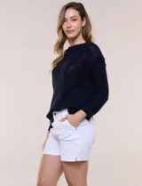 Buzo liviano de algodón con tejido de punto abierto y semi holgado, color beige, con escote bote, mangas largas de hombros caídos y costuras expuestas.