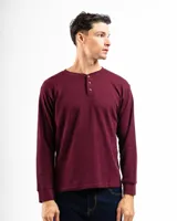 Remera tipo henley de manga larga confeccionada en tejido de algodón con textura mini piqué. Presenta un cierre frontal con tres botones y puños ajustados en las mangas.